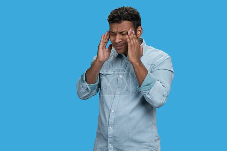 Photo for Young indian man touching his head because of headache or migraine pain. Isolated on vivid blue background. - Royalty Free Image