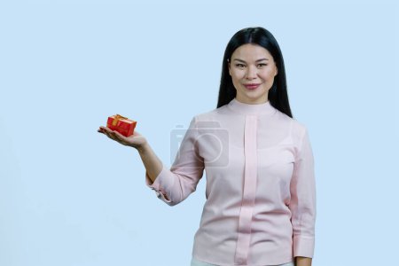 Téléchargez les photos : Heureuse jeune femme asiatique tenant boîte cadeau. Isolé sur fond bleu pastel. Recevoir des cadeaux d'amants. Nouvel An Noël et Saint Valentin concept. - en image libre de droit