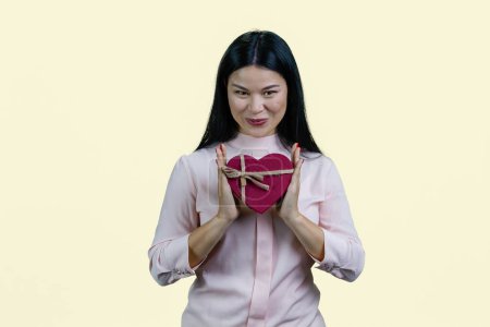 Photo for Young korean woman holding heart shape gift box in both hands. Isolated on white background. - Royalty Free Image