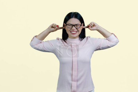 Téléchargez les photos : Portrait d'une jeune femme asiatique mettant des doigts dans ses deux oreilles. Isolé sur fond blanc. - en image libre de droit