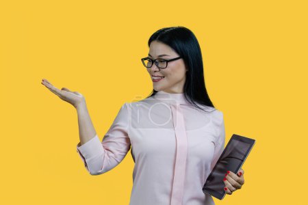 Foto de Mujer asiática feliz en gafas está sosteniendo la tableta pc. Publicidad espacio de copia con palmera. Aislado sobre fondo amarillo. - Imagen libre de derechos