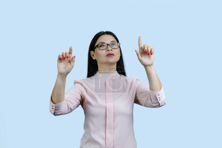 Foto de Joven mujer de negocios asiática está utilizando pantalla táctil invencible. Aislado en azul pálido. - Imagen libre de derechos