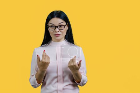 Photo for Portrait of a young asian woman is explaining herself. Isolated over yellow background. - Royalty Free Image