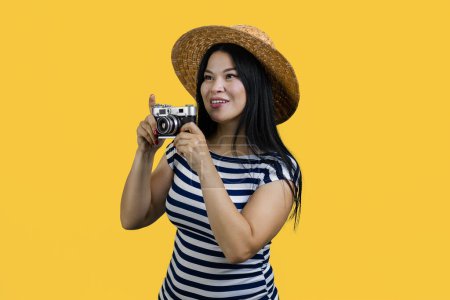 Photo for Young brunette asian lady with retro photo camera. Amazed korean tourist isolated on yellow. - Royalty Free Image