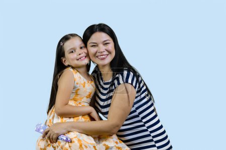 Téléchargez les photos : Heureuse femme asiatique avec sa petite fille caucasienne adoptée. Isolé sur fond bleu. - en image libre de droit