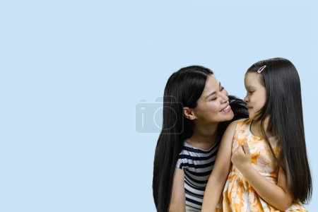 Téléchargez les photos : Portrait d'une mère asiatique heureuse avec sa petite fille. Isolé sur fond bleu. - en image libre de droit