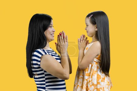 Photo for Side view of a young mother and her daughter are playing clapping game cutout. Isolated on yellow. - Royalty Free Image