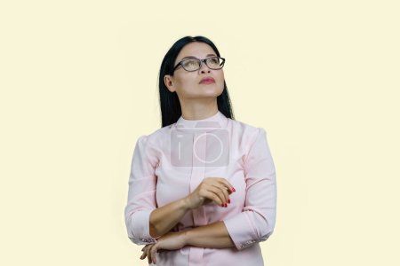 Téléchargez les photos : Portrait d'une jeune femme d'affaires asiatique coûteuse lève les yeux. Isolé sur jaune pastel. - en image libre de droit