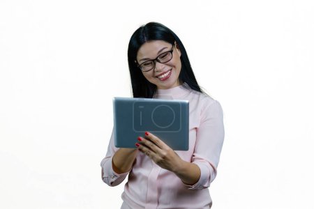 Photo for Young smiling asian businesswoman having online conversation via tablet pc. Cheerful korrean nerdy girl with modern device. Isolated on white background. - Royalty Free Image
