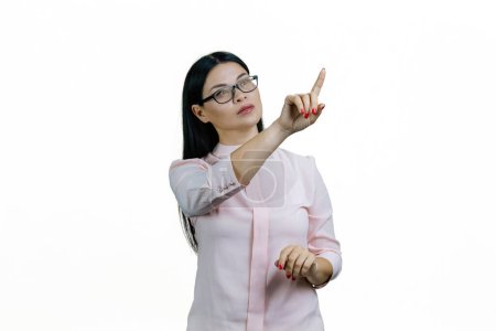 Téléchargez les photos : Jeune femme asiatique intelligente touche écran virtuel invisible avec son doigt. Isolé sur fond blanc. - en image libre de droit