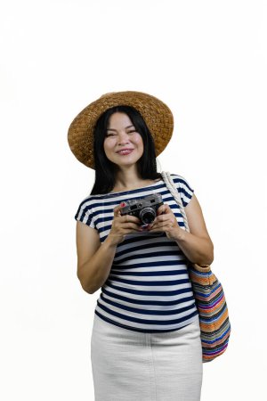 Foto de Tiro vertical de mujer asiática con sombrero de paja está sosteniendo la cámara de fotos vintage. Aislado sobre blanco. - Imagen libre de derechos