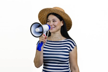 Téléchargez les photos : Femme asiatique en chapeau de paille parle quelque chose dans un mégaphone. Isolé sur blanc. - en image libre de droit