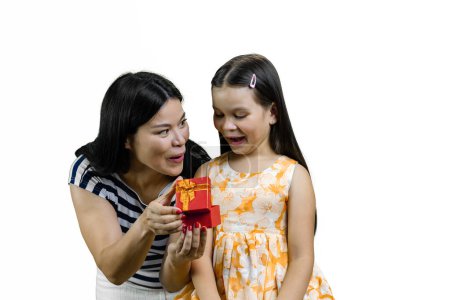 Téléchargez les photos : Jeune mère asiatique avec sa petite fille ouvrir une boîte-cadeau rouge ensemble. Isolé sur blanc. - en image libre de droit