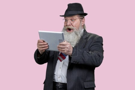 Photo for Portrait of shocked aged man with tablet pc. Isolated on pink. - Royalty Free Image
