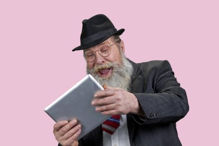 Foto de Retrato de la risa anciano anciano con la tableta de PC. Feliz abuelo con artilugio moderno. Aislado n rosa. - Imagen libre de derechos