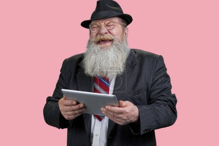 Téléchargez les photos : Portrait d'homme âgé heureux riant avec tablette pc. Isolé n rose. - en image libre de droit
