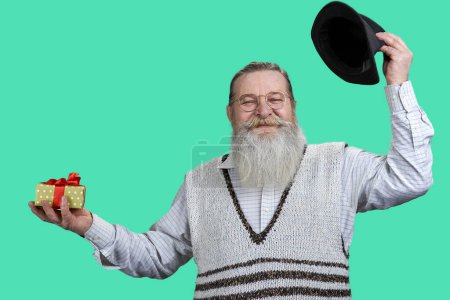 Photo for Portrait of senior aged man raising up his hat. Isolated on green background. - Royalty Free Image