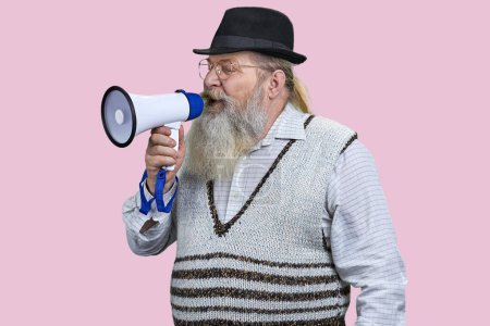 Téléchargez les photos : Portrait d'un homme barbu âgé faisant une annonce en mégaphone. Isolé sur rose. - en image libre de droit