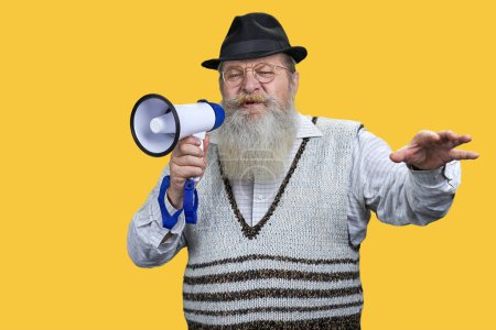 Photo for Portrait of old aged man giving a speech in megaphone. Isolated on vivid yellow background. - Royalty Free Image