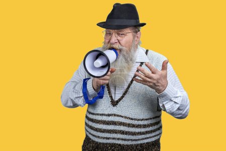 Téléchargez les photos : Portrait d'un homme âgé expressif donnant un discours en mégaphone. Isolé sur fond jaune vif. - en image libre de droit