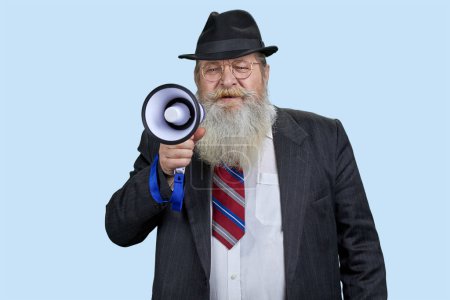 Téléchargez les photos : Portrait d'un homme âgé criant en mégaphone. Fond bleu pastel. - en image libre de droit