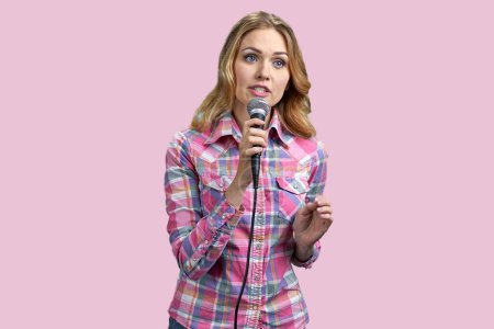 Foto de Retrato de una joven cantante con micrófono. Aislado sobre fondo rosa. - Imagen libre de derechos
