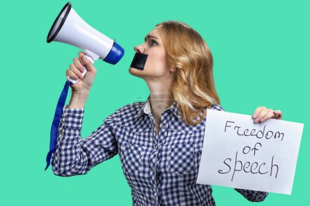 Téléchargez les photos : Jeune femme blonde tenant un mégaphone et une bannière avec inscription sur la liberté d'expression. Isolé sur fond vert. - en image libre de droit