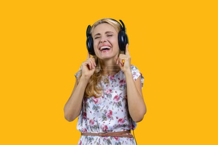 Téléchargez les photos : Femme blonde aime la musique dans les écouteurs. Isolé sur jaune. - en image libre de droit