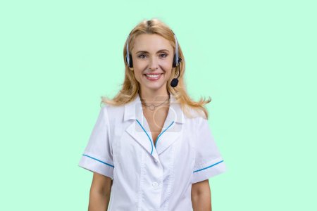 Photo for Portrait of happy blonde doctor wearing headset. Isolated on turquoise. - Royalty Free Image
