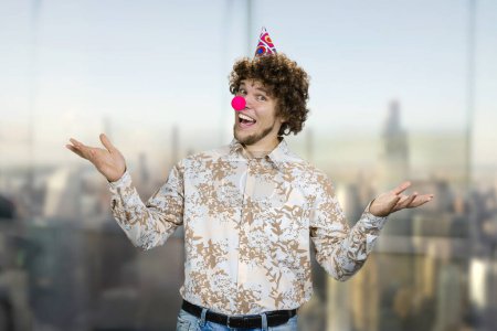 Téléchargez les photos : Portrait d'un jeune caucasien aux cheveux bouclés portant un nez de clown. Joyeux anniversaire concept. - en image libre de droit