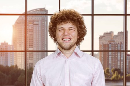 Photo for Portrait of a happy young cheerful man with curly hair. Cityscape view in the background. - Royalty Free Image