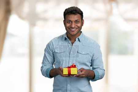 Photo for Handsome smiling man holding gift box and looking at camera. Birthday present for her. - Royalty Free Image