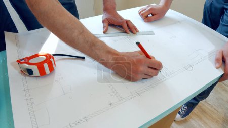 Téléchargez les photos : Deux ouvriers élaborent un plan de la maison. Le projet est dessiné sur papier. - en image libre de droit