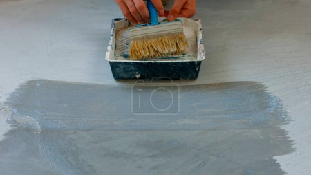 Foto de Casa pintor imprimación piso de hormigón. Trabajador preparando el suelo bajo la pintura. - Imagen libre de derechos