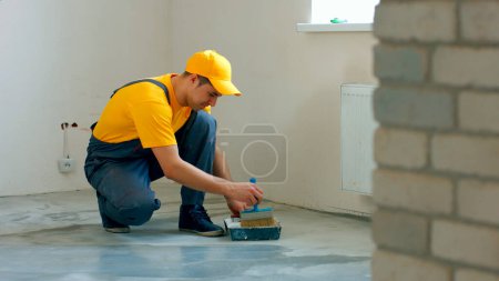 Téléchargez les photos : Le constructeur prépare le sol. Travailleur faire la rénovation de l'appartement. - en image libre de droit
