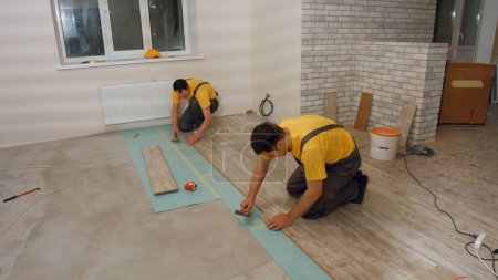 Photo for Workers lay the floor in the house. Laying laminate. - Royalty Free Image