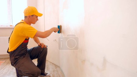 Photo for Builder covers the wall with wallpaper glue. Repair in the house. - Royalty Free Image