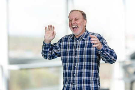 Portrait of handsome middle aged man is laughing out loud. Bright indoor background.