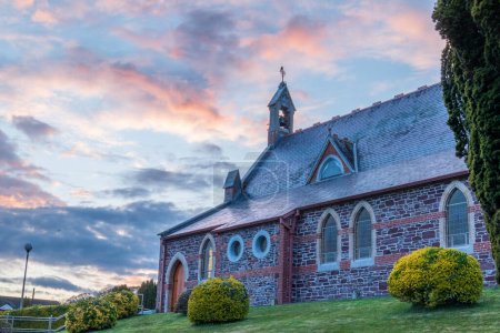 Die Kirche wurde aus tiefem Winkel gegen den roten Himmel fotografiert. Steinbau mit roten Ziegeln und Bogenfenstern.