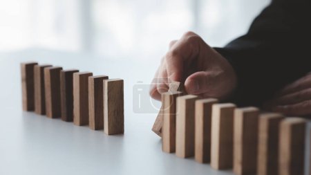 Photo for A close-up shot of a businessman holding the wooden blocks in a row, the wood blocks compare to the business risk management. The concept of risk management. copy space. - Royalty Free Image