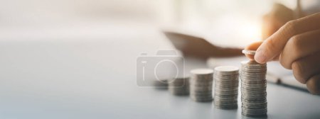 Photo for A person is holding coins in five rows from low to high, he is accounting for income and expenses and dividing her savings. Concept of saving money and investing it to grow money. - Royalty Free Image