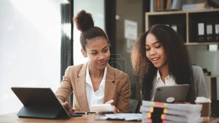 Photo for Two American women are working together in the office of a startup company. They are having a brainstorming and planning meeting in a joint department, women leading the way. Concept of women's work. - Royalty Free Image