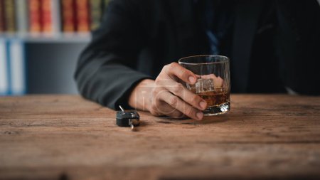 Téléchargez les photos : Homme tenant un verre de brandy, il boit du brandy dans un bar, boit de l'alcool nuit à la capacité de conduire et peut nuire à la santé. Le concept de consommation d'alcool. - en image libre de droit