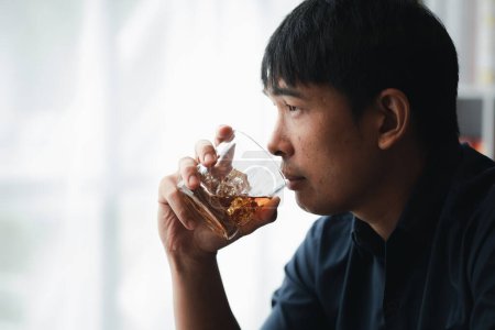 Photo for Man holding a glass of brandy, he is drinking brandy in a bar, drinking alcohol impairs driving ability and can damage health. The concept of drinking alcohol. - Royalty Free Image
