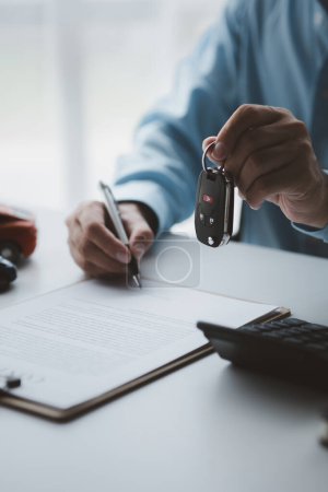 Foto de A car rental company employee pointed out the renter to sign the rental agreement after discussing the details and rental terms with the renter. Concept of car rental. - Imagen libre de derechos