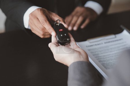 A car rental company employee pointed out the renter to sign the rental agreement after discussing the details and rental terms with the renter. Concept of car rental.