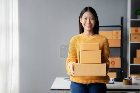 Photo for A beautiful business owner opens an online store, she is checking orders from customers, sending goods through a courier company, concept of a woman opening an online business. - Royalty Free Image