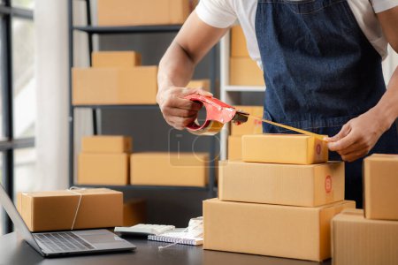 Photo for An online shop owner man is packing orders, he is an internet shop operator selling products through online shopping platform website. The concept of selling products on the internet. - Royalty Free Image