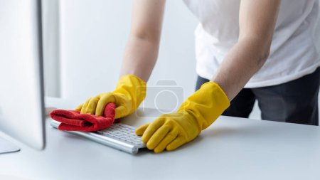 Photo for Person cleaning room, cleaning worker is using cloth to wipe computer keyboard in company office room. Cleaning staff. Concept of cleanliness in the organization. - Royalty Free Image