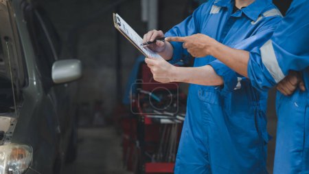Photo for Two professional car mechanics looking at car inspection papers together, all types of car specialists, expert car repairs and certified auto repair centers. - Royalty Free Image